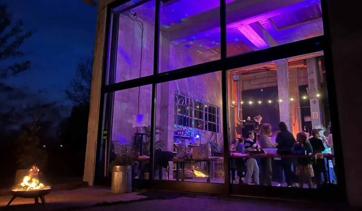 The Silo's glass front glowing purple at an evening event, with a fire pit outside